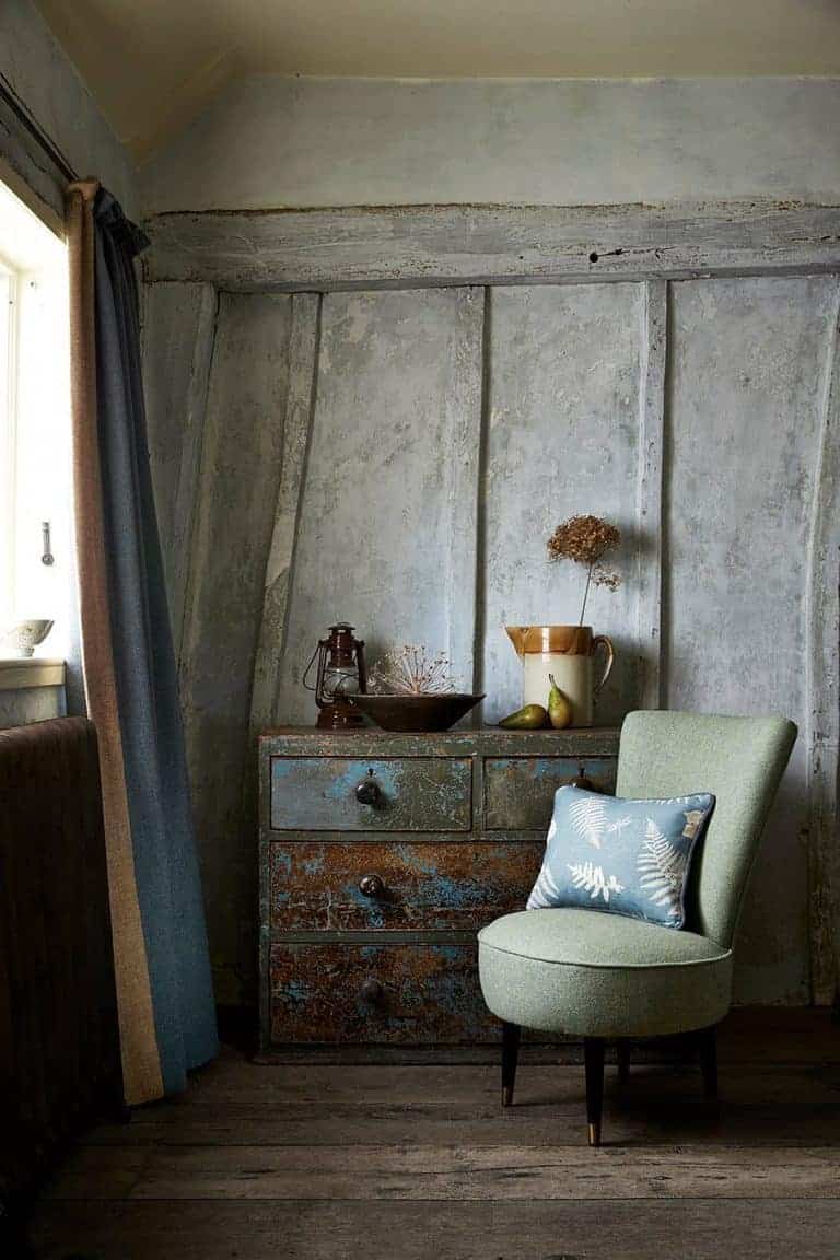 love this modern rustic living room with distressed walls vintage furniture and upholstered green chair with linen cushion