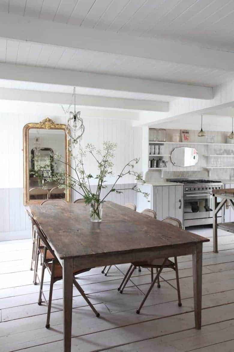 love this modern rustic coastal kitchen diner dining room with white washed painted tonque and groove panelled walls and lime washed floor boards with open shelving, rustic dark wooden dining table with vintage metal chairs and vintage mirrors vintage lighting and prints. Click through for more inspiring modern rustic decorating ideas you'll love #modernrustic #decorating #kitchen #dining #vintage #country #white #frombritainwithlove