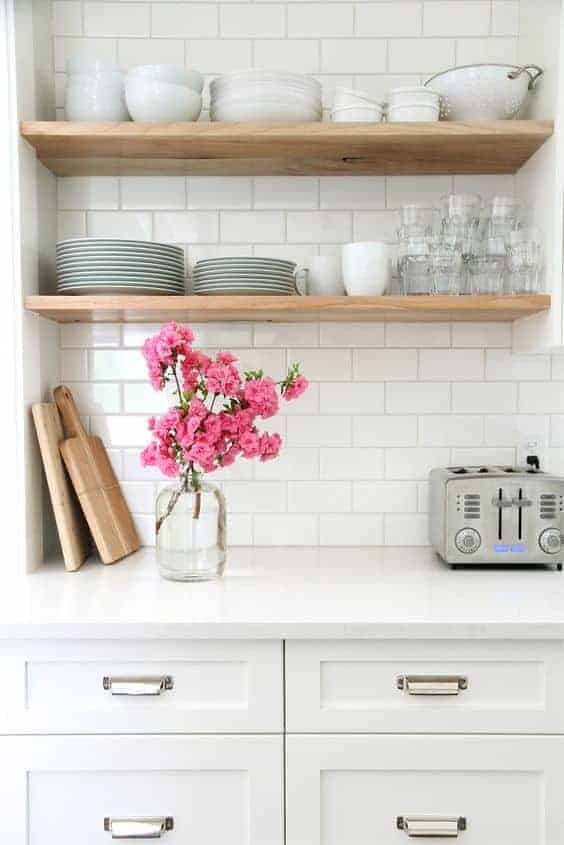 love this white country kitchen with open shelves in pale wood with stacked crockery and simple glasses. Click through for more contemporary country kitchen ideas you'll love