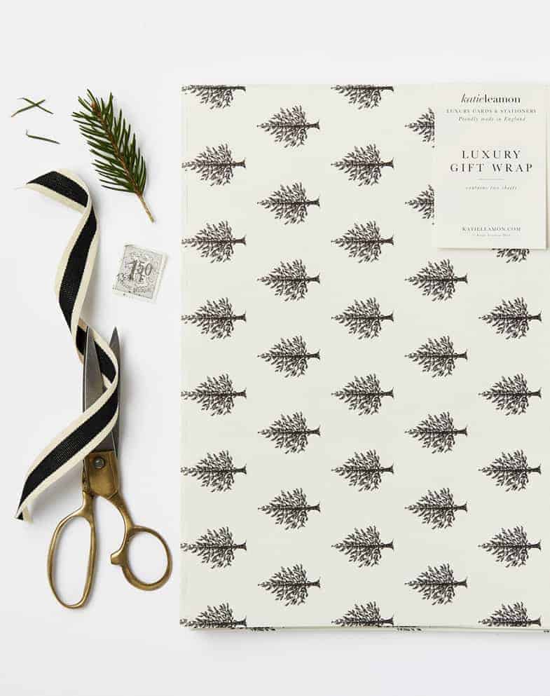 love this simple black and white christmas tree print scandi gift wrap with black ribbon fresh foliage and pine cones by katie leamon. Click through for more ethical eco-friendly and plastic free christmas gift wrapping ideas you'll love to try