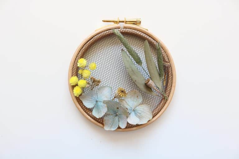 How to make embroidery hoop art with dried flowers. Olga Prinku shares her simple step by step DIY tutorial to create your own mini hoop with hydrangea, eucalyptus, mimosa and spring flowers. Click through for other stunning ideas you'll love to try too #embroideryhoop #embroideryhoopart #driedflowers #frombritainwithlove #olgaprinku #DIY #tutorial #howtomake #embroideryhoopcraft #ideas