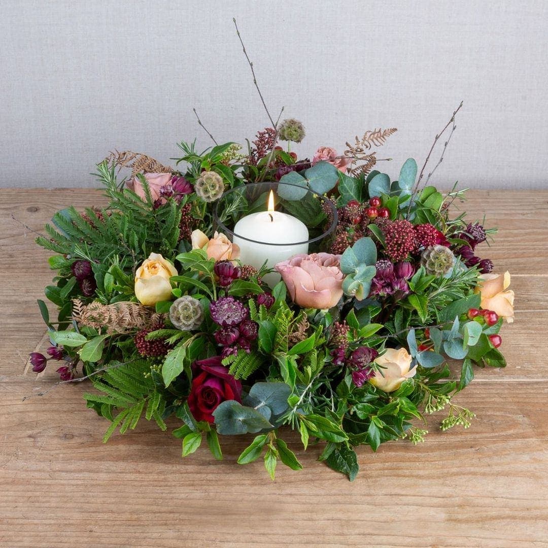 christmas centrepiece by the real flower company in copper, plum and gold with roses and seasonal foliage