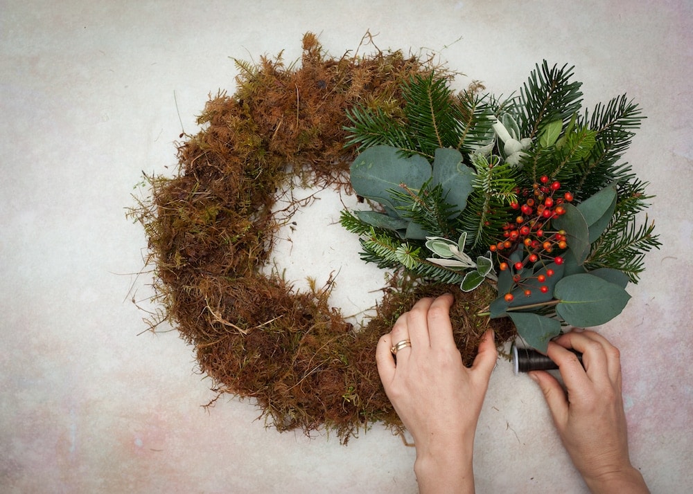 how to make a christmas centrepiece with fresh foraged festive greenery, holly, berries and foliage with expert step by steps and tutorial by the real flower company. Add a candle and you're good to go
