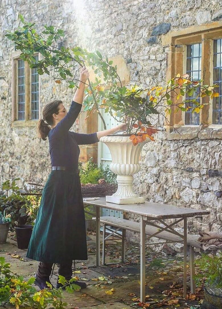 sarah diligent of floribunda rose florists demonstrating how to create autumnal seasonal urns with fall flowers and leaves