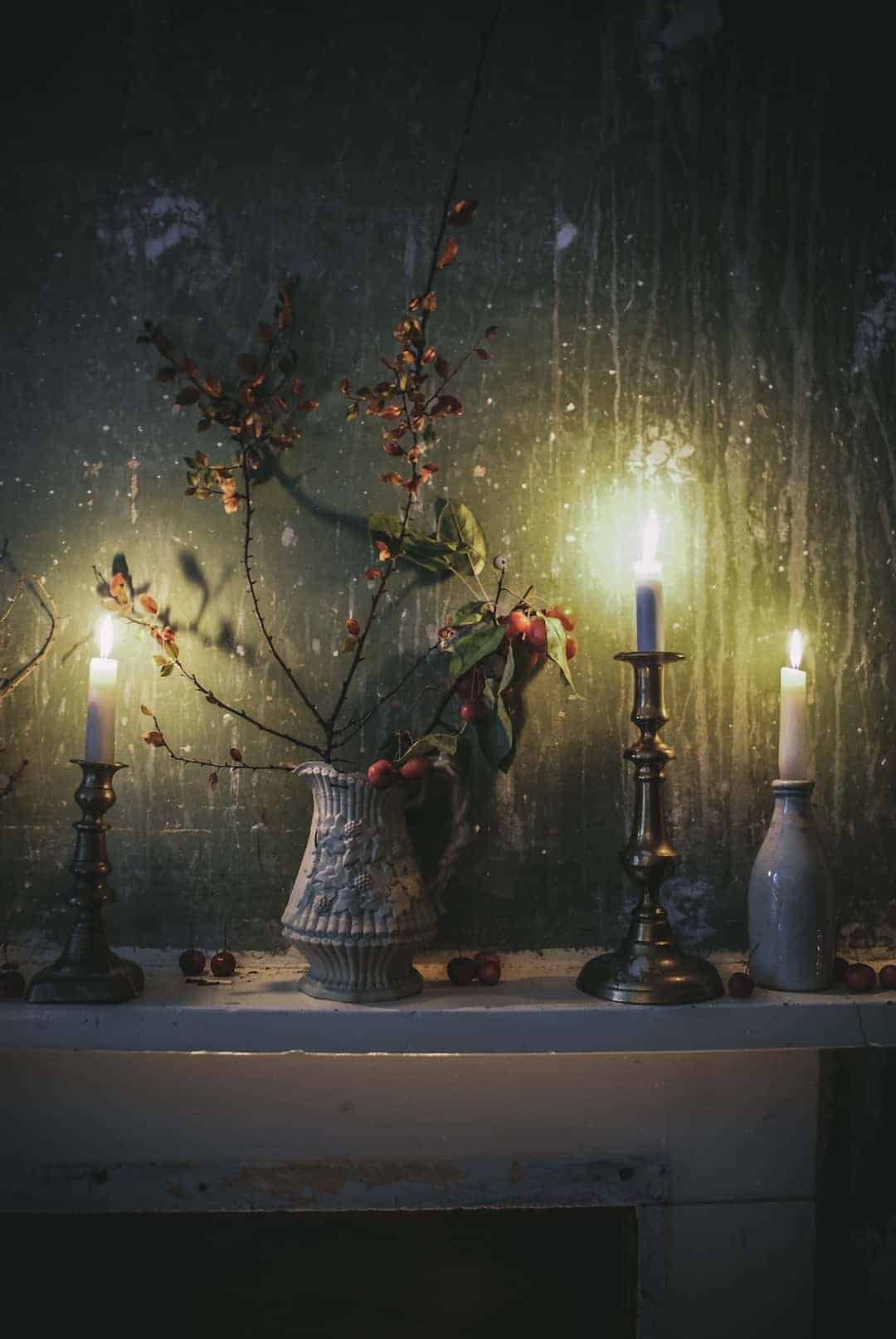love this moody candle light and distressed plaster wall with crab apples and old jugs on mantelpiece at old regency window with linen and wooden clothes pegs at The Regency Townhouse for the launch of Conscious Creativity by Philippa Stanton aka @5ftinf. Click through for a peek inside and a look behind the scenes at the launch workshop