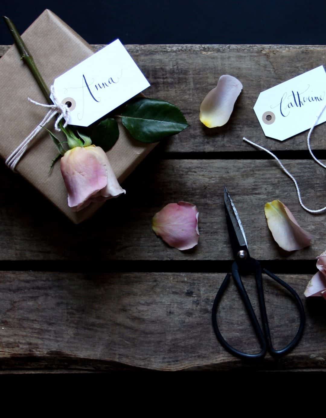 love this idea of combining brown kraft paper with pretty fresh pink roses and hand claligraphy luggage label gift tags. Click through for more ethical eco-friendly and plastic free christmas gift wrapping ideas you'll love to try 