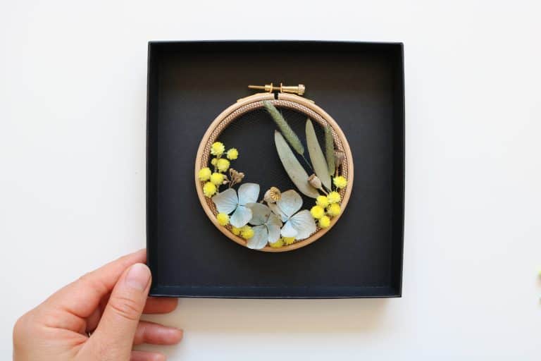 How to make embroidery hoop art with dried flowers. Olga Prinku shares her simple step by step DIY tutorial to create your own mini hoop with hydrangea, eucalyptus, mimosa and spring flowers. Click through for other stunning ideas you'll love to try too #embroideryhoop #embroideryhoopart #driedflowers #frombritainwithlove #olgaprinku #DIY #tutorial #howtomake #embroideryhoopcraft #ideas
