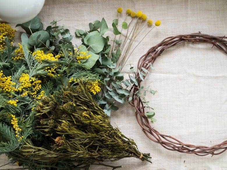 how to make a spring flower wreath for easter - click through for easy step by step tutorial as well as super helpful video guide to making the most beautiful spring flower garland wreath with yellow mimosa, and other easter and spring flowers #springflowers #wreath #easter #easterdecorations #springwreath #frombritainwithlove #flowerideas #wreathideas