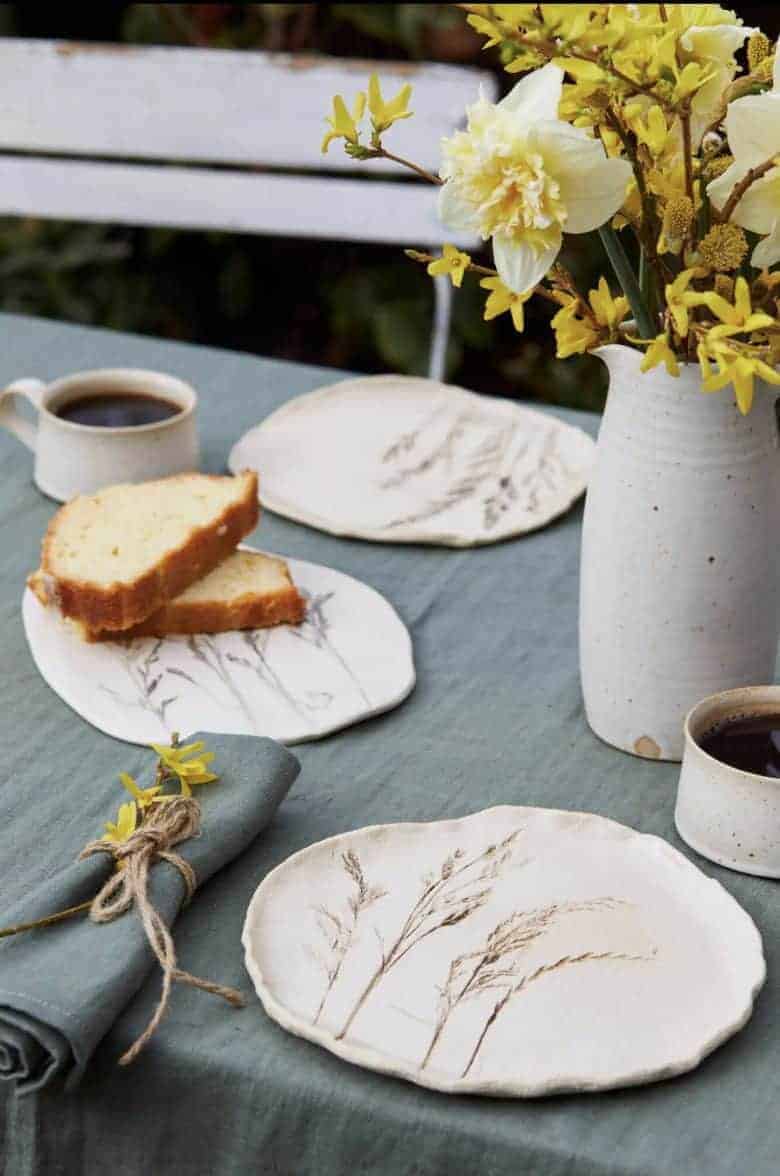 Meadow grass print stoneware ceramic side plates by julie reilly for these two hands handcrafted in England with the imprint of wild grasses with ruffled edges and glazed with a cream-white and oxides to highlight the pattern in stoneware clay #meadow #grass #ceramic #plate #juliereilly #handmade